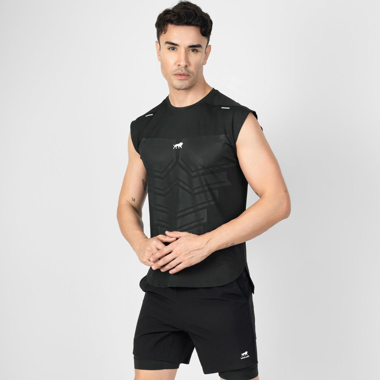Man wearing a black sleeveless shirt and shorts on a gray background